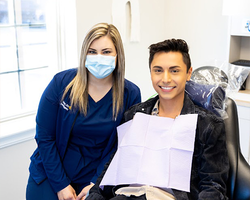 Dental team member and patient grinning after a smile makeover