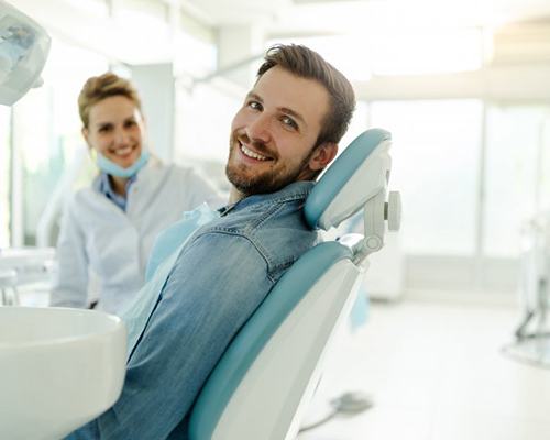 a patient and dentist smiling in the exam room