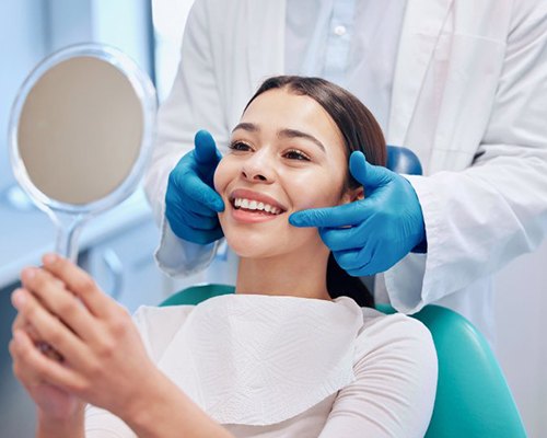 a patient checking her smile with a mirror