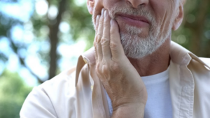 Close up of mature adult male rubbing his jaw at the park